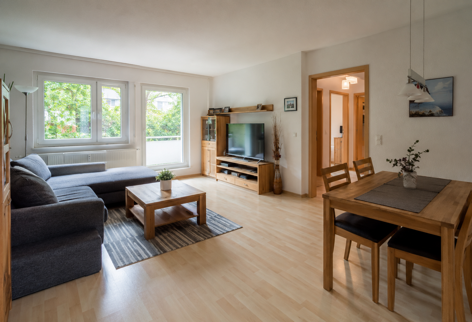 Helles Wohn- und Esszimmer mit Eckcouch, Holzmöbeln und Balkonzugang